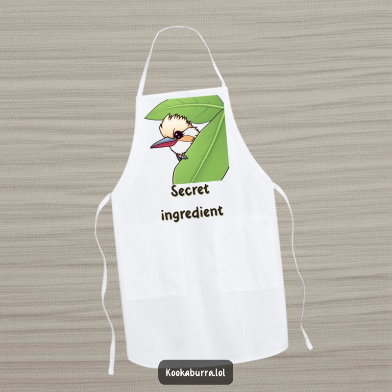 Funny apron with a kookaburra peeking from behind a giant leaf, giving a mischievous wink, perfect for playful chefs.