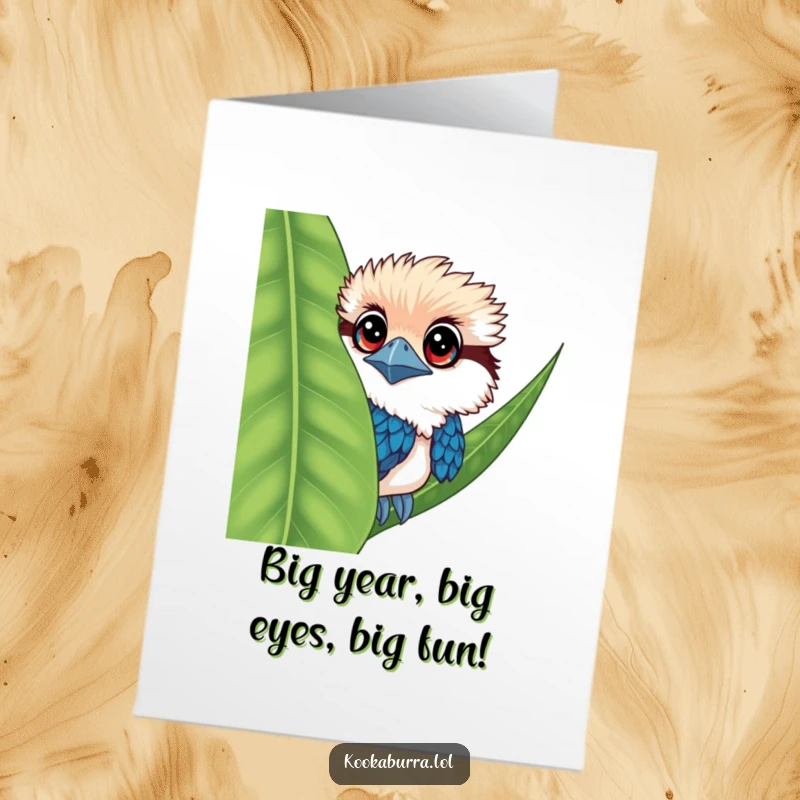 Funny Free Printable Kookaburra Birthday Card: A kookaburra with wide, adorable eyes peeks playfully from behind a lush green leaf.