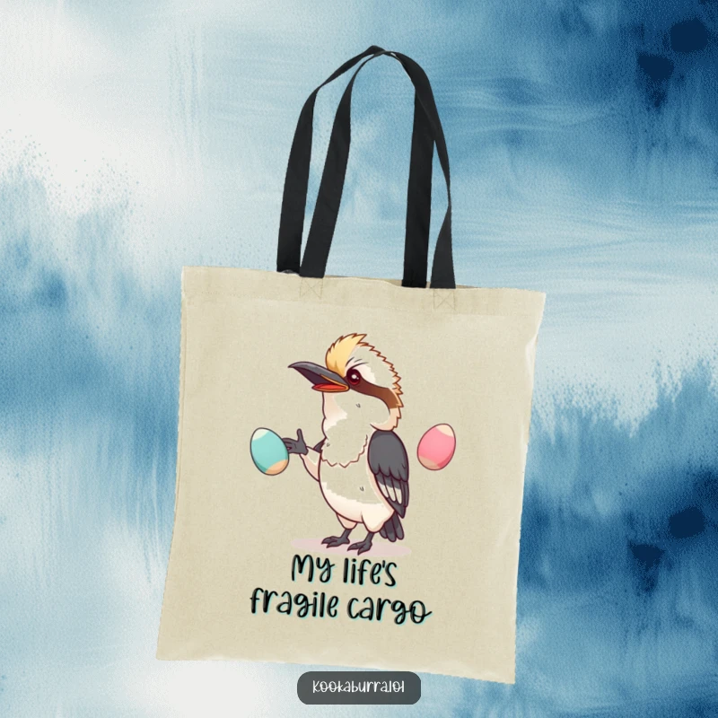 Funny tote bag featuring a kawaii kookaburra attempting to juggle oversized, wobbly eggs with a comical, determined expression.