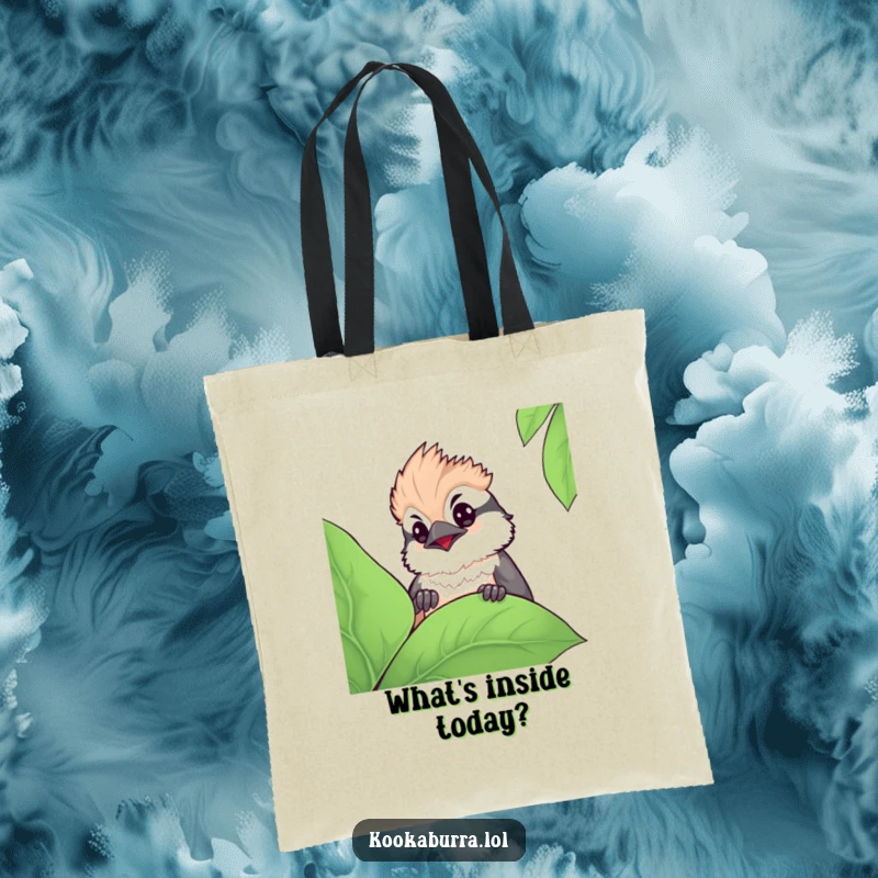 Funny kawaii kookaburra tote bag showing a cute bird curiously peeking from behind a large leaf, perfect for carrying essentials in style.